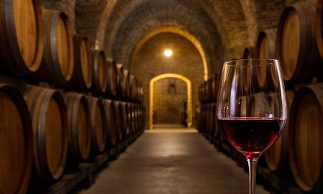 Bodega centenaria de La Rioja con barricas de roble y copa de vino