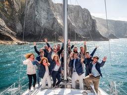 Grupo corporativo navegando en barco frente a los acantilados de la costa vasca